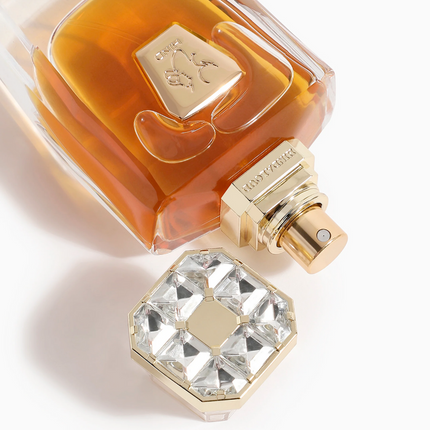 Perfume bottle with gold cap and crystal design on a white background